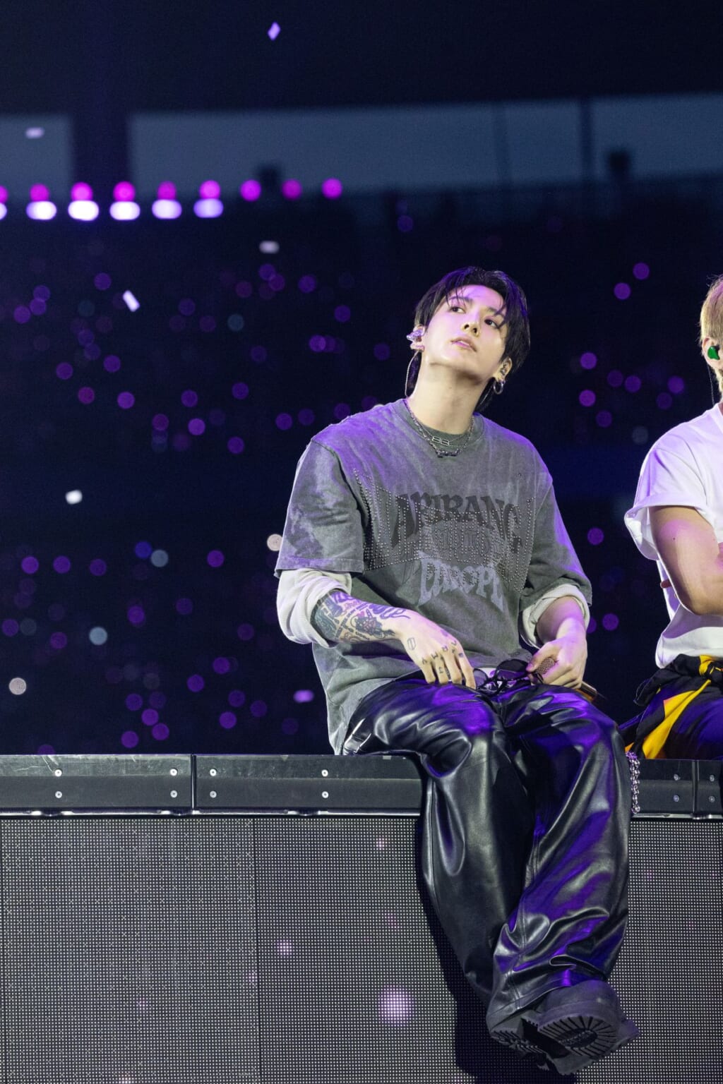 BTS ARIRANG: Inside the Looks of the World Tour Vanity Teen 虚荣青年 Jung Kook of BTS wearing a gray Balenciaga logo T-shirt with studded lettering and leather trousers.