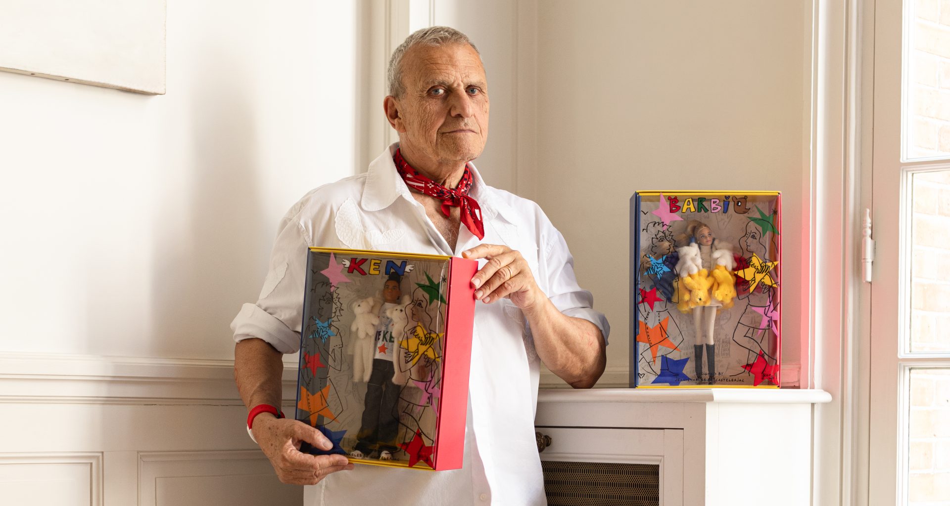 Jean-Charles de Castelbajac holding Barbie and Ken dolls in his studio